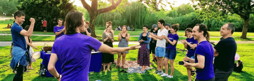 People celebrating and smiling outdoors at a park on a sunny day